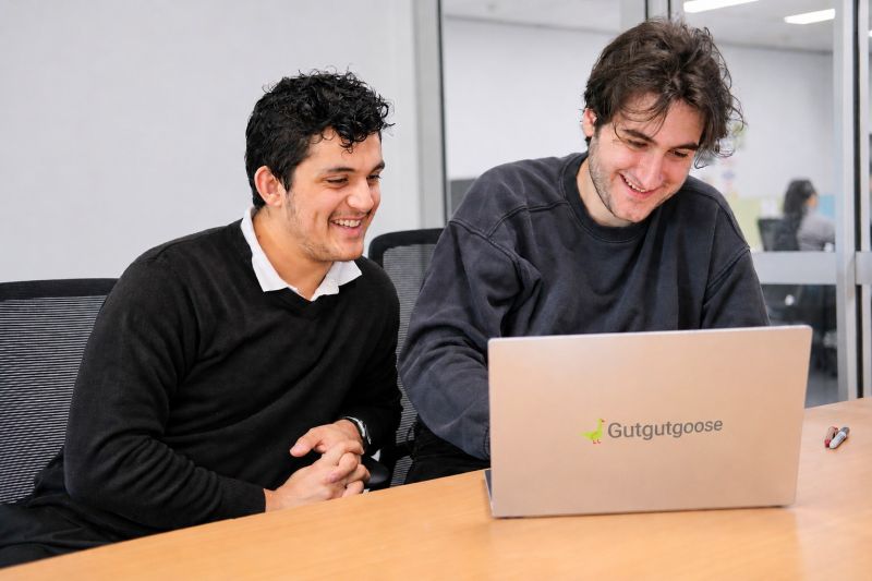 GutGut Goose co-founders looking at a Gutgutgoose-branded laptop together at a desk